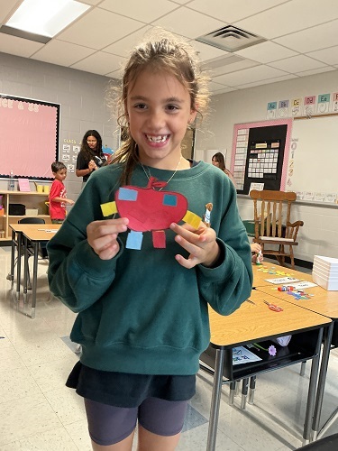 School age child proudly showing the human she made