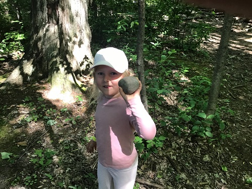 Child holding rock up proudly
