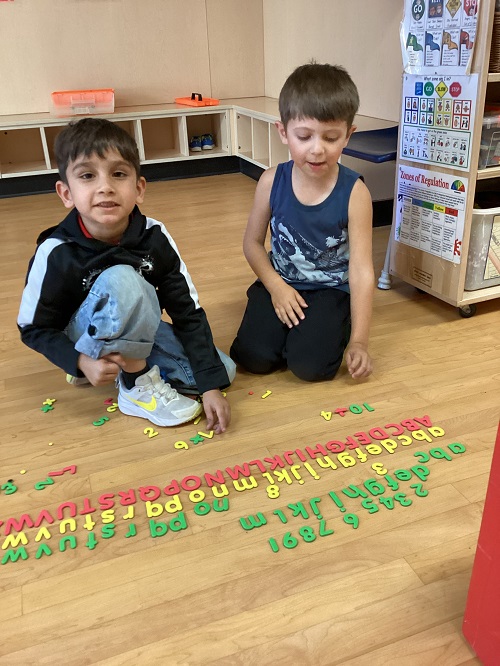 children lining up letter and number magnets