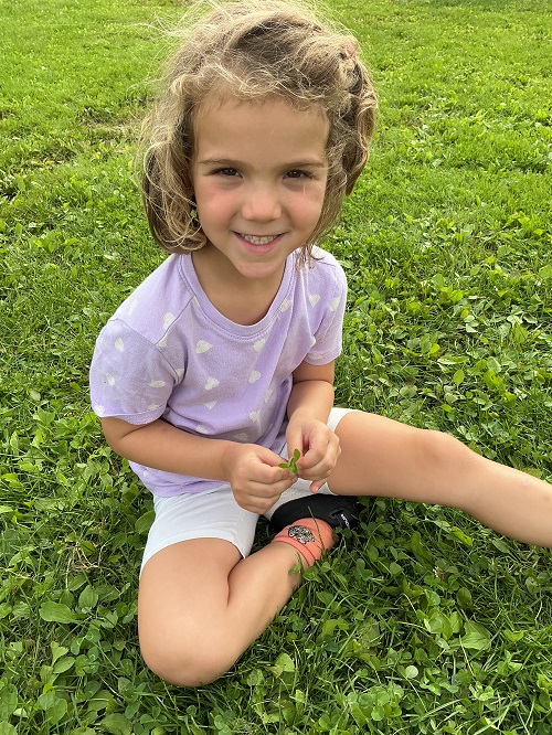 child sitting in the grass with a four leaf clover