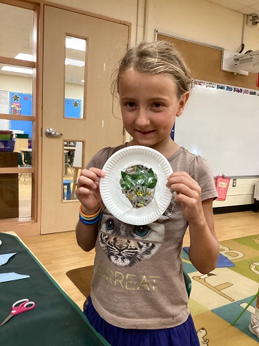 Child holding up their paper plate moon art