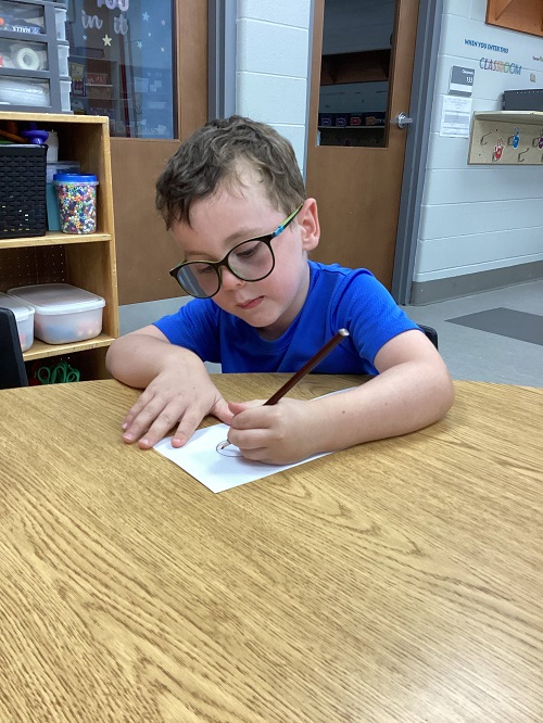 child sitting at the table drawing on their template